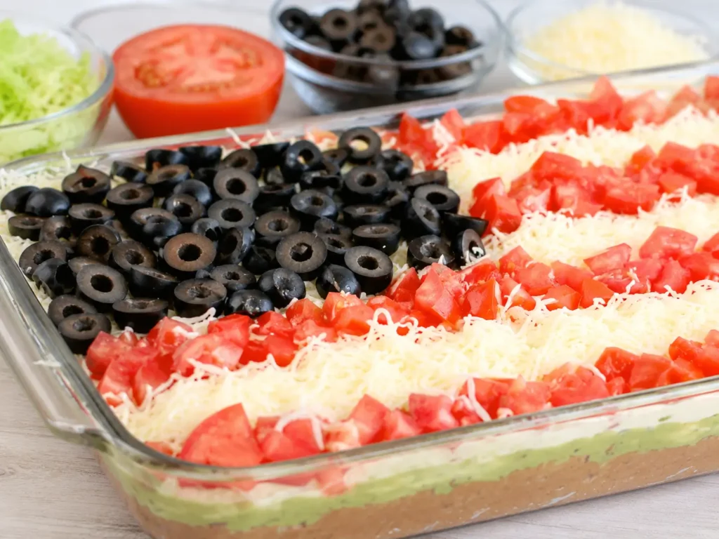 American Flag Layered Taco Dip topped with tomatoes, mozzarella, and black olives