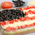 American Flag Layered Taco Dip topped with tomatoes, mozzarella, and black olives