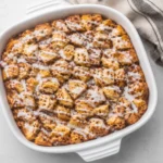 Warm Cinnamon Roll Casserole with icing drizzle in baking dish