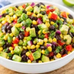 Colorful bowl of Cowboy Caviar with beans, corn, avocado, and lime dressing