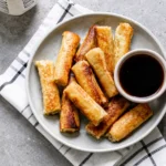Golden French Toast Roll-Ups served warm with syrup on a breakfast plate