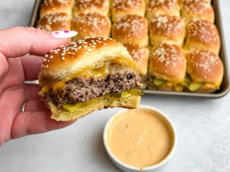Hawaiian Roll Cheeseburger Sliders with melted cheese and pickles on a baking tray