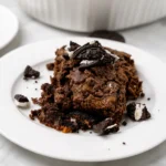 Warm Oreo Dump Cake topped with whipped cream and crushed cookies