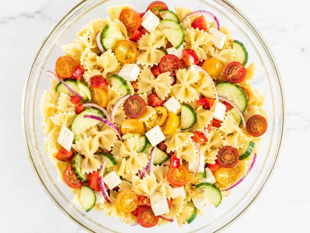 Fresh Pasta Salad with tomatoes, cucumber, mozzarella, and Italian dressing in a serving bowl