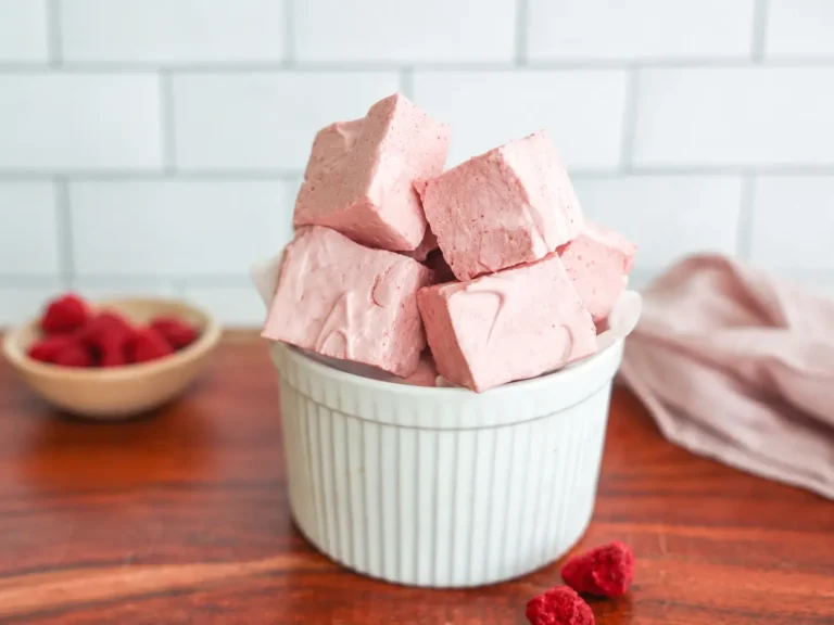 Soft homemade Raspberry Marshmallows stacked on a plate with fresh raspberries