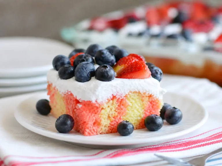 Strawberry Jello Flag Cake topped with whipped cream, strawberries, and blueberries