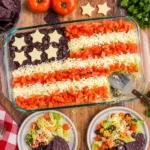 Taco Salad Flag layered dip topped with tomatoes, mozzarella, and blue tortilla chips