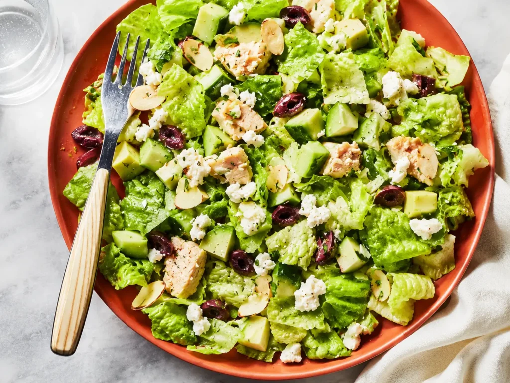 Avocado Tuna Salad served in a bowl with feta, cucumber, olives, and toasted almonds