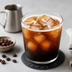 Freshly made Iced Americano in a clear glass with espresso, water, and ice