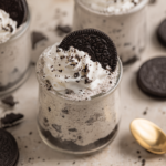 Oreo Cheesecake Cups topped with whipped cream and crushed cookies in glass dessert cups